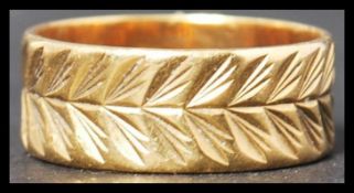 An 18ct gold band ring with a chased decorated finish weighing 5 g and measuring