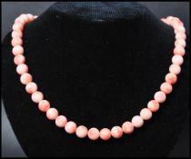 A vintage angel skin coral necklace. The necklace of graduating form each bead carved and strung set