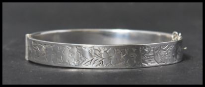 A silver hallmarked vintage ladies bangle bracelet having a half engraved foliate design with hidden