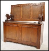A mid 20th century oak Jacobean revival Monks bench having carved lions to both sides with lift up