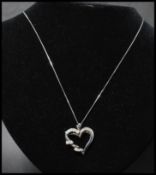 A 14ct white gold and diamond pendant necklace strung with a diamond set heart shaped pendant  on