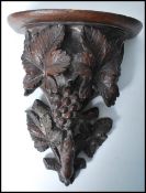 A 19th century Black Forest carved pine wall bracket, with shaped and moulded shelf, supported by