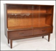 An retro 1970's teak wood glazed display cabinet having a pair of smoked glass sliding doors above a