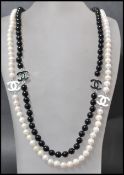 A long row of black and white freshwater pearls having enamel spacers with pendant attached