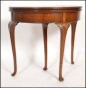 A 1930's good quality mahogany and walnut inlaid demi lune games - card table being raised on
