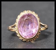 A hallmarked 9ct gold ring set with a faceted cut amethyst stone in a rope twist mount. Weighs 3.5