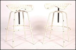 A pair of contemporary retro Industrial stools with tractor seat tops on swivel columns and