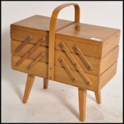 A vintage mid 20th century retro metamorphic sewing box with contents being raised on tapering legs