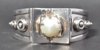 A signed Taxco Mexican modernist silver bangle bracelet set with a pearl having a clip clasp. Marked