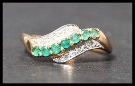 A hallmarked 9ct gold diamond and emerald crossover ring. Hallmarked Birmingham. Weight 2g. Size R
