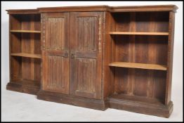 An early 20th century oak breakfront bookcase cabinet. Raised on a plinth base with upright bookcase