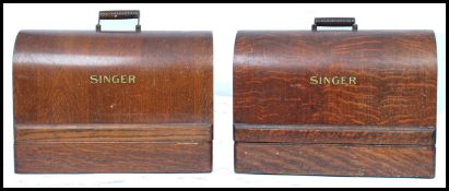 A pair of early 20th century hand crank Singer sewing machines, both machines with wooden dome carry