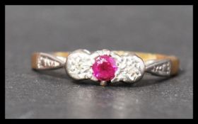 A 18ct gold platinum ruby and diamond three stone ring having stylised shoulders. Marked 18ct