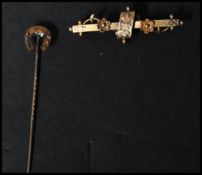 A 19th century 15ct gold stick pin along with a 9ct gold bar brooch. The pin with horse shoe to