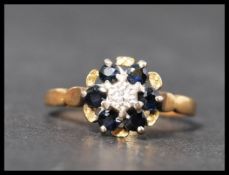A hallmarked 18ct gold diamond and sapphire cluster ring having a central illusion cut diamond wit a
