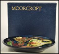 A Moorcroft ceramic pin tray coaster plate of circular form tube lined decorated with flowers in the