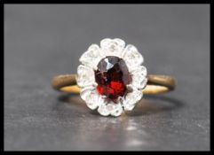 A hallmarked 18ct gold diamond and garnet stone cluster ring having a central faceted stone with a