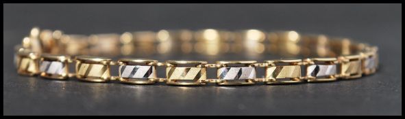 A hallmarked white and yellow gold bracelet with alternating white and yellow gold frosted chevron