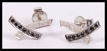 A pair of 18ct white gold and diamond sapphire earrings of crossover channel set diamonds with studs