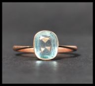 An early 20th century 9ct rose gold ring set with a single cushion cut pale blue stone. Marked 9ct