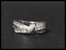A hallmarked 9ct white gold and CZ ring having square and round cut CZ in a crossover setting.