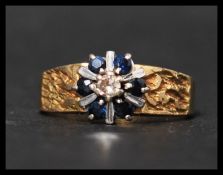 An 18ct gold sapphire and diamond ring with central diamond surrounded by a halo of sapphires,