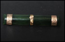 A Victorian 9ct gold and jade bar brooch, the jade being mounted with three gold bands with etched