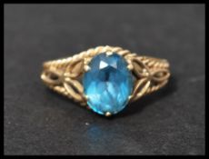 A hallmarked 9ct gold and blue topaz ring set with an oval cut blue topaz in rope twist and stylised