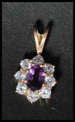A hallmarked 9ct gold cluster pendant set with a central oval cut amethyst surrounded by  halo of