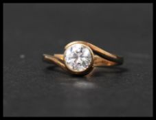 A hallmarked 9ct gold solitaire ring with a large white stone in a crossover bezel setting.