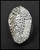 A large white metal Swarovski crystal dress ring having paved set crystals of a graduated grey and