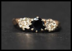 A hallmarked 9ct gold sapphire and diamond trilogy ring set with a central round cut sapphire