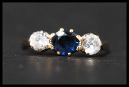 A hallmarked 9ct gold blue sapphire and white stone trilogy ring. Hallmarked London. Size O.5