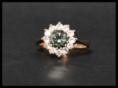 A hallmarked 9ct gold cluster ring set with a central moss green stone surrounded by white stones.