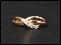 An 18ct gold and white stone ring set with five white stones in s crossover setting. Marks to