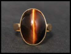 A hallmarked 14ct gold and tigers eye ring, set with a tigers eye cabochon with stylised