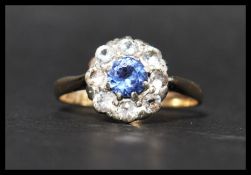 A 9ct gold blue and white stone cluster ring having a central round cut blue stone surrounded by a