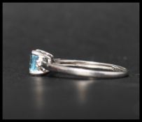 A hallmarked 9ct white gold ring set with a cushion cut pale blue stone flanked by two round cut