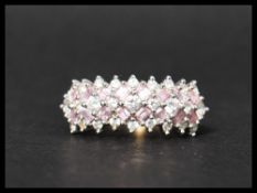 A hallmarked 14ct gold ring set with white round cut stones interspersed with pink baguette cut