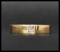 A hallmarked contemporary 18ct gold and diamond band ring set with two baguette cut diamonds.