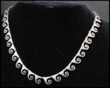 A 925 silver necklace featuring a fancy wave link motif chain having a lobster claw clasp. Marked