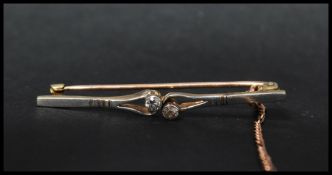 An Edwardian 9ct gold platinum and diamond bar brooch being set with two bezel mounted old cut