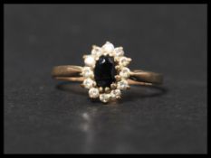 A hallmarked 9ct gold ring with central oval cut sapphire surrounded by a CZ halo . Hallmarked