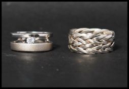 Two 925 silver band rings one having a weave design the other having a suspension set white stone.