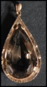 A large vintage 9ct gold pendant set with a pear cut smokey quartz in a pierced setting.  Marked