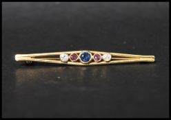 An 18ct gold 5 stone bar brooch being set with a central blue sapphire flanked by two pink sapphires