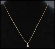 An 18ct gold and diamond drop pendant necklace strung with an square cut diamond on a box link