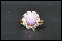A 14ct gold cluster ring set wit a central pink opal style stone surrounded by a halo of white