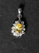 A  18ct white gold pendant set with a yellow stone surrounded by a halo of white stones. Marked