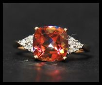 A hallmarked 9ct gold diamond and orange mystic topaz ring having a central cushion cut topaz